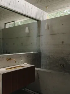 Industrial-style bathroom with concrete walls and floor, featuring a minimalist sink and metal fixtures.