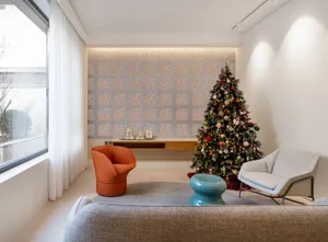 A minimalist living room decorated for the holidays with a Christmas tree adorned with lights and ornaments, along with a sue