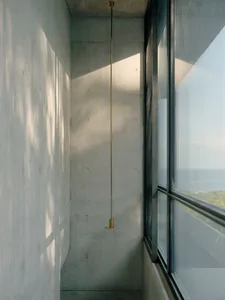A minimalist balcony with a concrete wall and a floor-to-ceiling window.