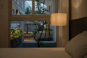 A contemporary bedroom with textured wallpaper and plants.