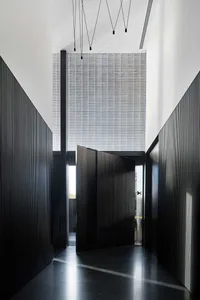 Modern black wooden door entry with concrete floor and large window.