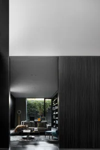 A modern living room with metallic black paneled walls and minimalist decor.