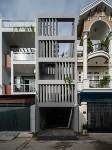 A modern residential entryway featuring a concrete structure with open, tiered levels and greenery on balconies.