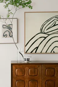 A modern interior showcasing an abstract artwork with black lines and a wooden cabinet.