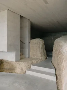 Contemporary architecture featuring concrete and rock elements within an interior space.