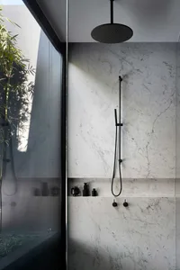 Modern minimalist bathroom with marble walls, black faucet, and concrete floor