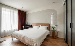 A minimalist bedroom with a white bed, wood headboard, and cotton-blend bedding.