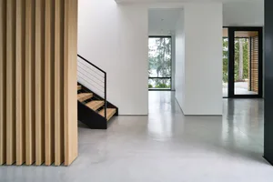 Contemporary minimalist home entrance featuring wood staircase and floor-to-ceiling windows.