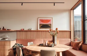 Modern minimalist dining room with a round wooden table, chairs, and a bench seating area.