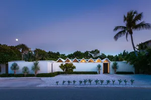 A modern residential exterior with concrete walls and white gravel pathway.