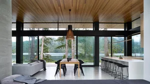 A modern residential space featuring a dining area with a wooden table and black chairs, a sofa, and a kitchen counter with s
