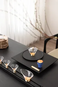 A meticulously arranged tea ceremony setup with glassware, ceramic items, and metal accents on a black table.