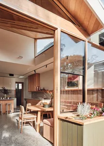 Modern kitchen dining room with wood accents and glass windows.