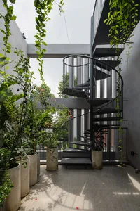 A modern interior space featuring a black metal staircase surrounded by potted plants and greenery.