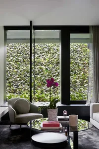 Modern living room featuring glass and leather furniture with green wall design