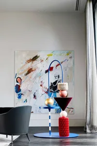 A modern interior design featuring metal furniture and sculpture against a white wall.
