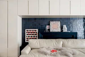 A modern living room with a blue tile backdrop and a white sectional sofa.