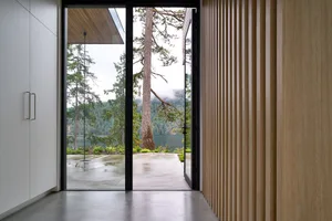 Minimalist-designed room featuring glass walls and natural wooden elements.