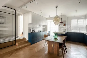 Modern minimalist kitchen with wooden flooring, glass cabinetry, and metal accents.