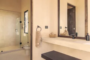 A minimalist bathroom featuring natural stone walls and flooring, complemented by a simple sink and mirror.