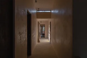 An empty minimalist hallway with concrete walls and a long, light-filled corridor.