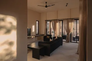 Minimalist living room with fabric sofa, wooden coffee table, and glass doors overlooking outdoor patio.