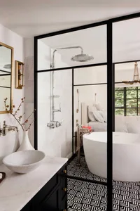 Modern bathroom with a white marble sink, black and white geometric floor tiles, and a white bathtub.