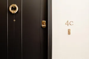 A modern black door with a golden brass handle and lock.