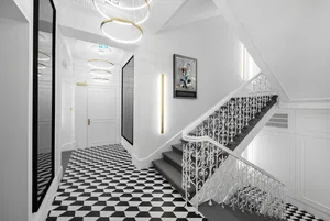 A modern hallway with black and white patterned floor, white walls, and a metal wire railing.