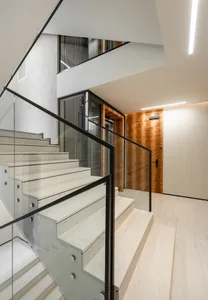 A modern interior design featuring a staircase with concrete steps and glass railings.