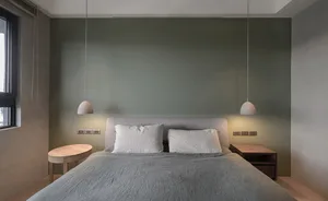 A modern, minimalist bedroom with concrete walls, a bed, and pendant lights.