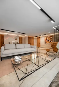 Modern minimalist living room with a glass coffee table and beige sofa, showcasing sleek design and contemporary style.