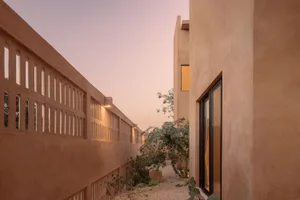 Modern residential exterior with sandstone walls and landscaping.