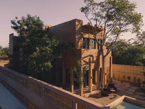 Modern residential house made of sandstone with a courtyard and trees.