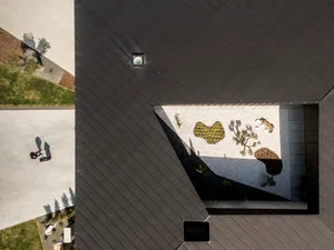 Top-down view of a modern rooftop garden featuring concrete and gravel surfaces with plants.