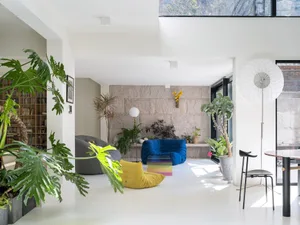 Industrial living room with concrete walls and floor, modern furniture, and plants.