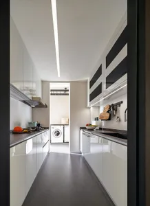 A minimalist kitchen with white cabinets and countertops.