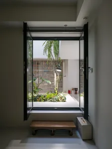 A modern minimalist interior featuring a stylish window garden, large window, white walls, and a wooden bench.
