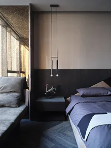 A modern bedroom with a textured wooden panel on the wall, featuring a bed with a blue duvet and a nightstand with a vase of 