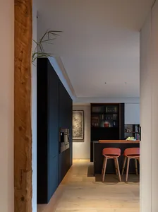 Modern, minimalist kitchen with black cabinetry and wood flooring