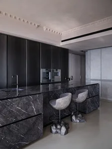 Modern kitchen with marble countertops, black cabinetry, and minimalist design.