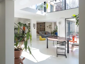 A spacious modern living room with concrete and glass elements.