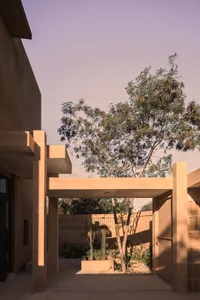 A modern exterior featuring concrete structures and a tree within a courtyard.