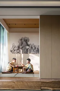 Two children playing a game on a wooden table in a modern living room with a natural stone mural on the wall.