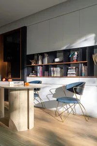 A modern living space featuring an open bookshelf with various books, decorative items, and a table with a stone base.