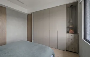 Modern minimalist bedroom featuring a bed with gray bedding and a large closet with gray panels.
