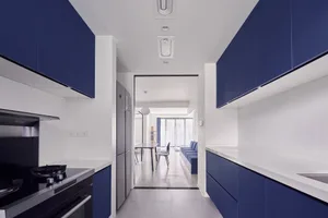 A modern kitchen with blue and white cabinets, white countertops, and stainless steel appliances.