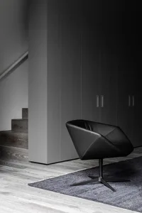 A black leather swivel chair with metallic legs in an industrial living space.