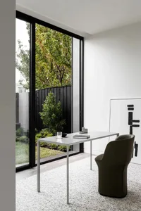 A minimalist home office featuring a metallic desk and wooden chair.