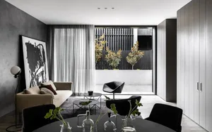 A minimalist living room featuring concrete walls and glass elements.